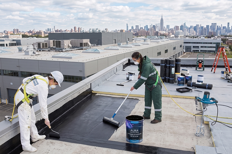Technician applying a waterproof roof coating